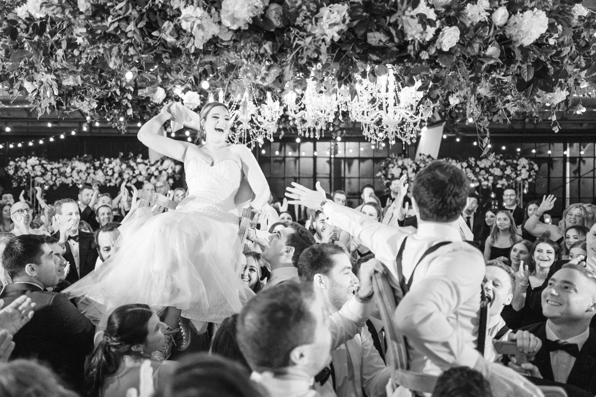 Wedding guests celebrating beneath flowers